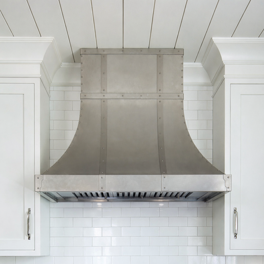 Stainless steel range hood in a kitchen with white tiled walls and cabinets.